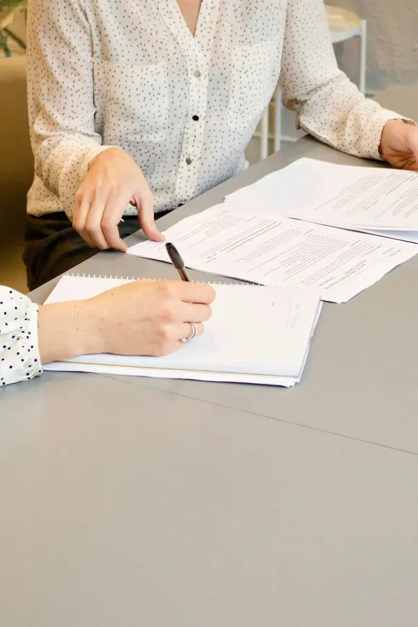 Two people at a table going over documents, one signing