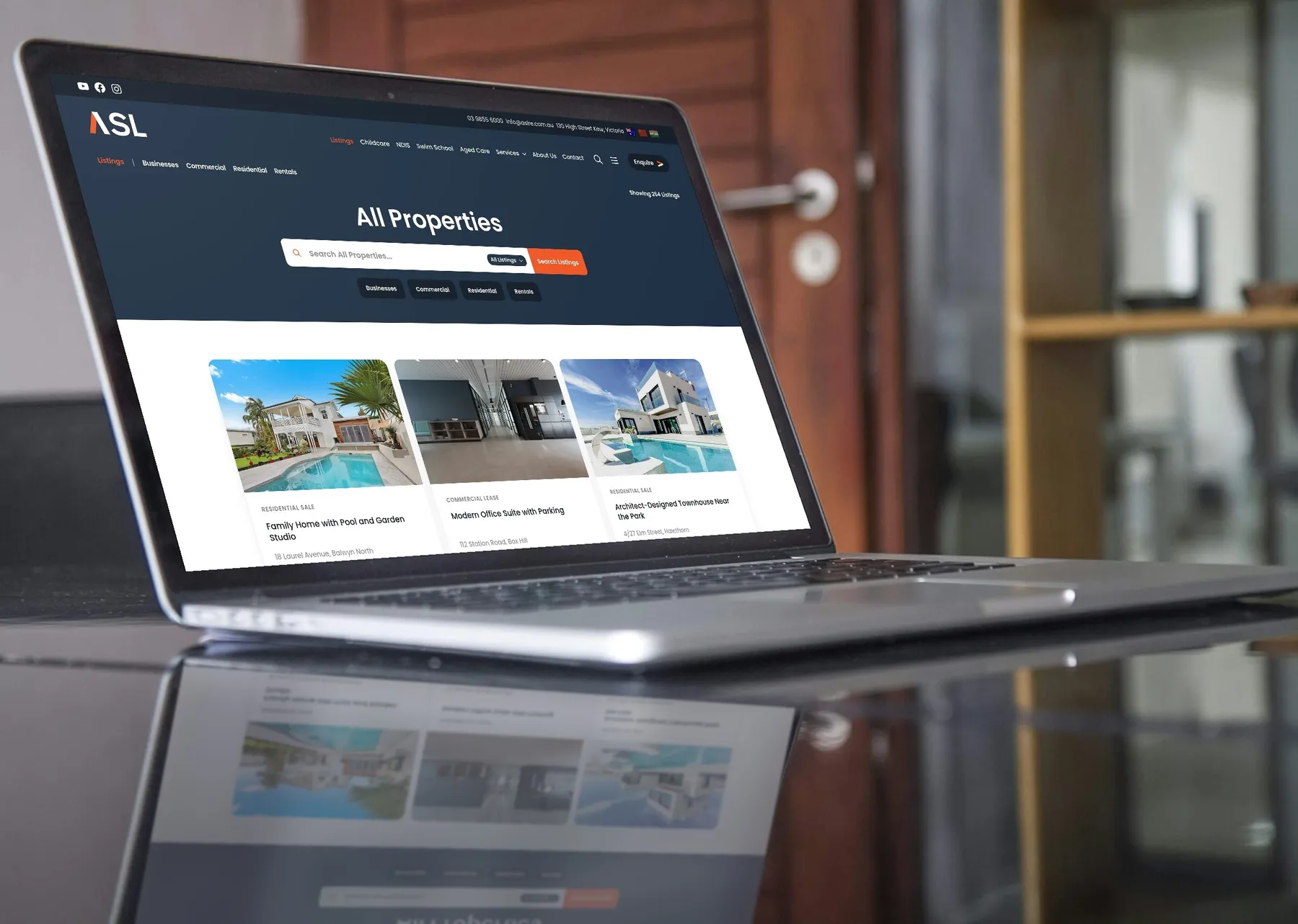 ASL Real Estate's listings page on a laptop, with sample listings